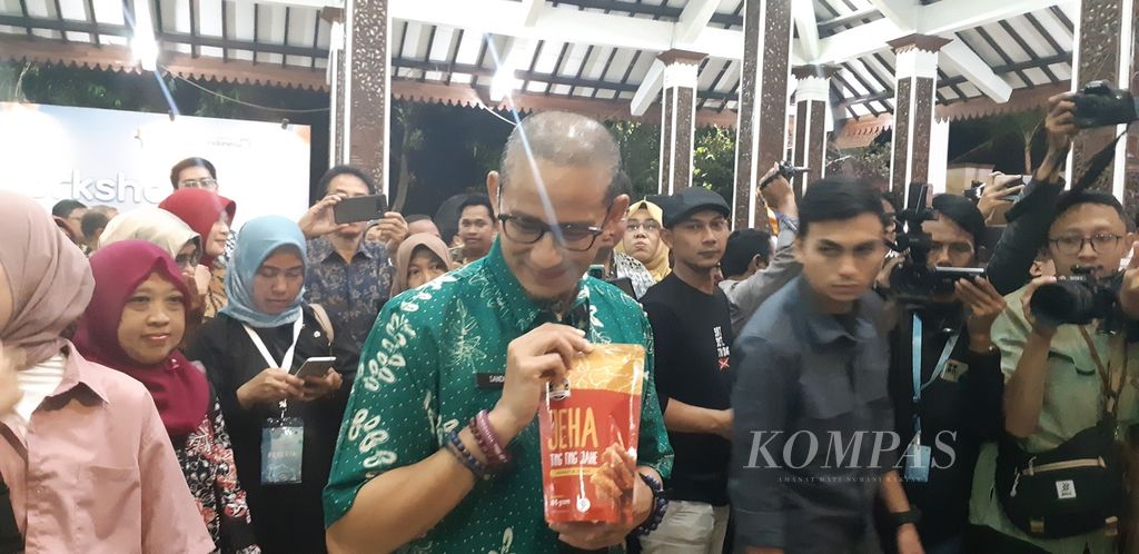 Menteri Pariwisata dan Ekonomi Keratif (Menparekraf) Sandiaga Salahudin Uno menunjukkan salah satu produk kuliner produksi UMKM kreatif Sidoarjo, Jawa Timur, Jumat (14/7/2023) malam. Kuliner seperti makanan ringan dan sambal menjadi bagian dari produk ekonomi kreatif unggulan Sidoarjo