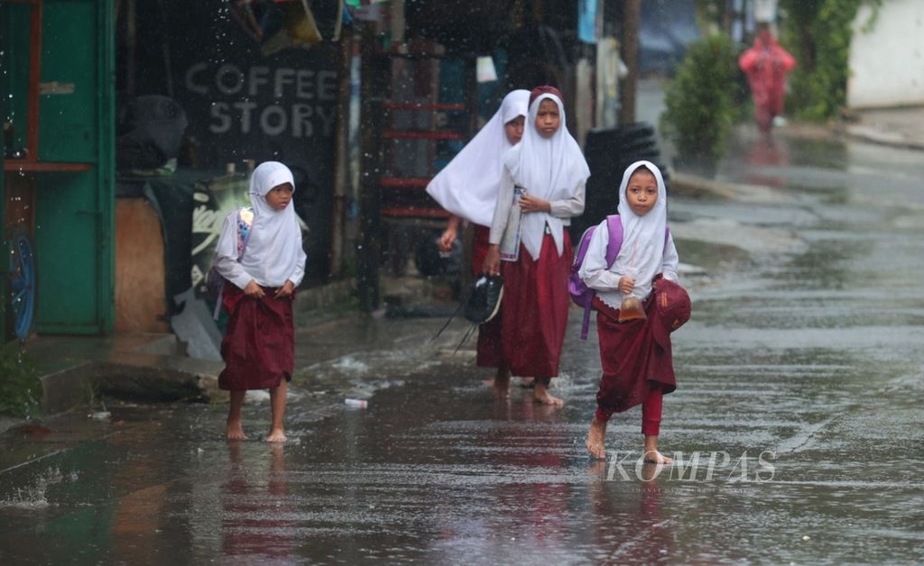 Siswa sekolah dasar pulang memembus hujan deras di kawasan Jombang, Tangerang Selatan, Banten, Selasa (28/3/2023).