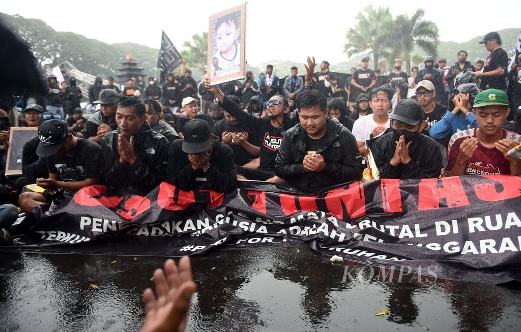  Aremania prays for the victims of the Kanjuruhan Tragedy during the "Malang Blackening" demonstration in Malang City Square, East Java, Thursday (10/11/2022). Aremania who followed the demonstration also brought coffins and photos of the victims who died.