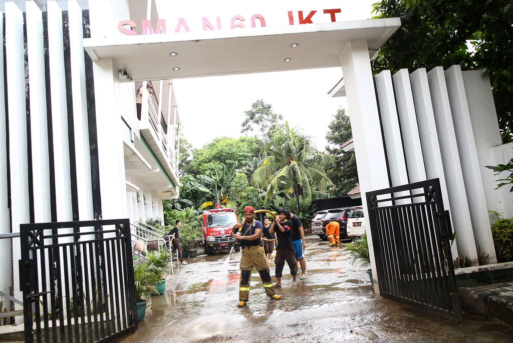 Petugas pemadam kebakaran membantu membersihkan lumpur setelah banjir surut di SMA Negeri 60, Mampang Prapatan, Jakarta Pusat, Rabu (26/2/2020). Banjir kerap kali merendam sekolah di kawasan Bangka, Mampang Prapatan, ini karena letaknya yang rendah dan berdekatan dengan Kali Mampang. 