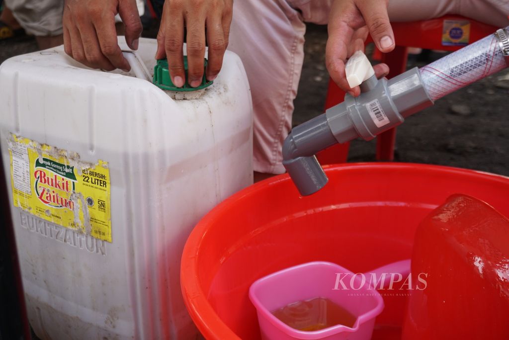 Petugas menutup jeriken minyak goreng yang telah terisi di Pasar Bersehati, Kelurahan Calaca, Manado, Sulawesi Utara, Kamis (28/4/2022). 