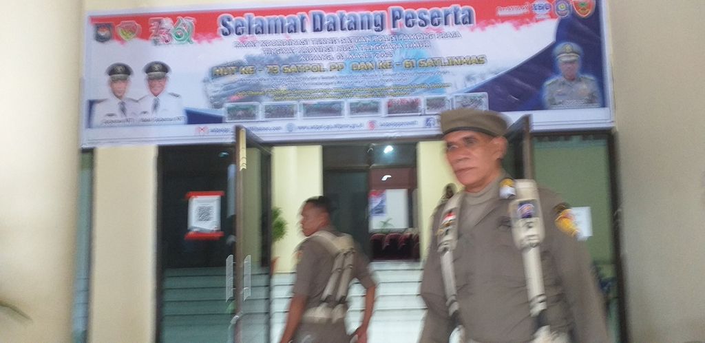 Salah satu anggota Satpol PP Provinsi NTT berfoto di pintu masuk ruang pertemuan Aula El Tari Kupang, Jumat (3/3/3023). 