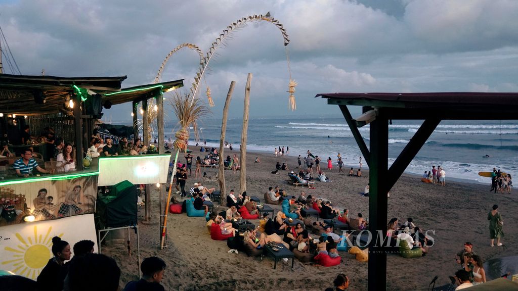 Wisatawan menikmati suasana sore hari di Pantai Batu Bolong, Badung, Bali, Minggu (26/6/2022). Wisatawan mulai berdatangan di Bali setelah pemerintah membuka keran perjalanan di tahun kedua pandemi Covid-19.