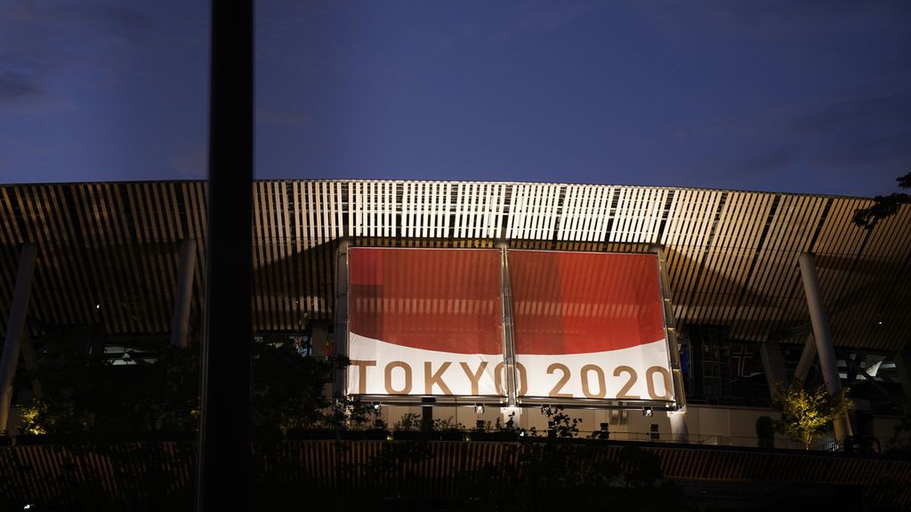 Spanduk besar Tokyo 2020 dipasang di fasad atas Stadion Olimpiade Tokyo yang menarik warga untuk mengambil foto, Kamis (22/7/2021). Stadion ini menjadi lokasi pembukaan Olimpiade Tokyo 2020 yang berlangsung di tengah pandemi Covid-19, Jumat (23/7/2021).