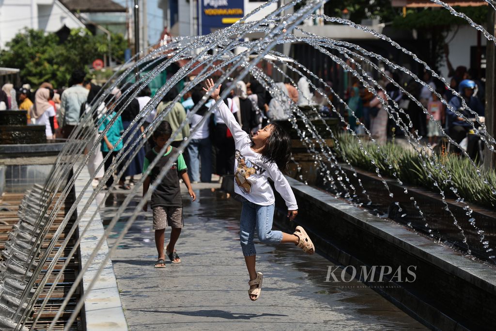 A child plays in the shower during sweltering hot weather at Taman Pintar, Yogyakarta, Saturday (4/5/2024).