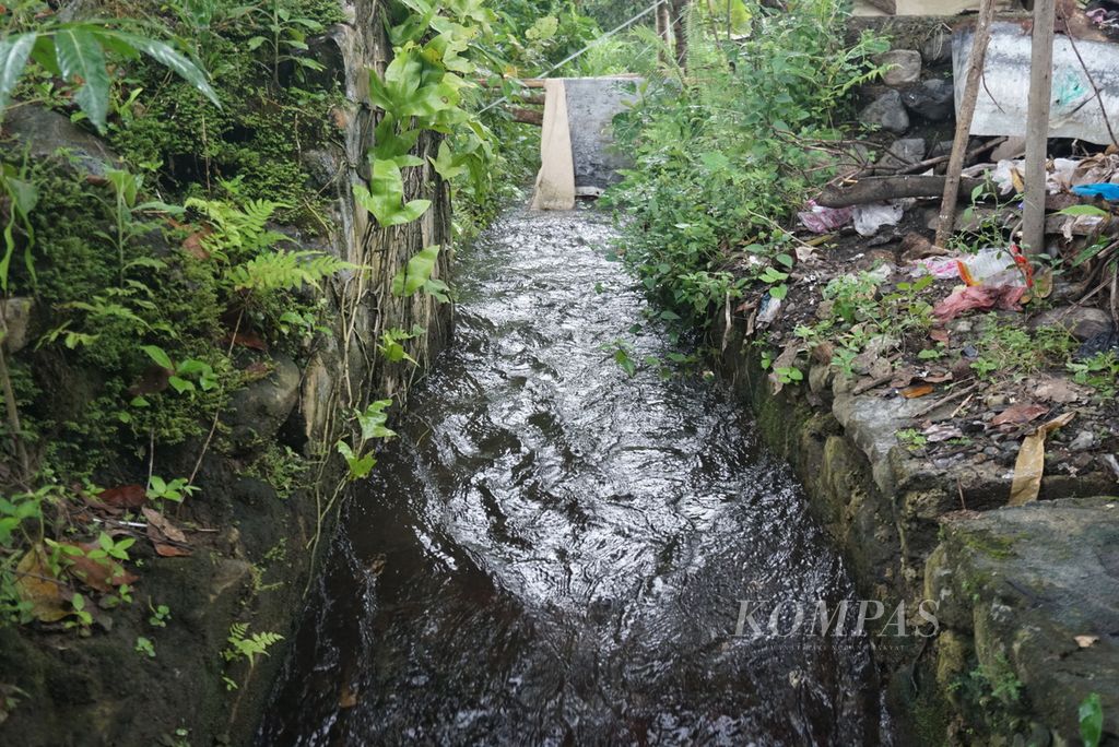 Air mengalir dalam saluran irigasi yang menjadi sumber tenaga pemutar kincir air pembangkit listrik tenaga mikrohidro, Kamis (14/7/2022), di Desa Mengkang, Kecamatan Lolayan, Bolaang Mongondow, Sulawesi Utara. Sejak listrik PLN masuk pada 2018, kincir air tak lagi digunakan.