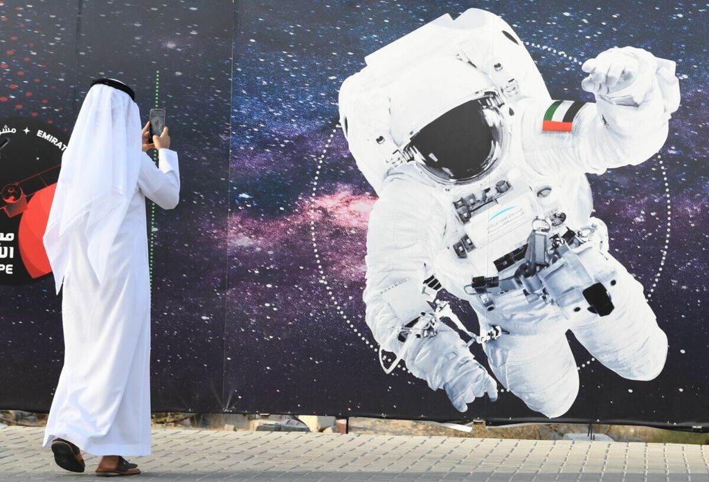 Seorang pria memotret foto ilustrasi yang menggambarkan astronot dengan bendera Uni Emirat Arab (UEA) di luar Pusat Luar Angkasa Mohammed bin Rashid, Dubai, UEA, 25 September 2019, menjelang penerbangan astronot UEA, Hazzaa al-Mansoori, ke luar angkasa. 