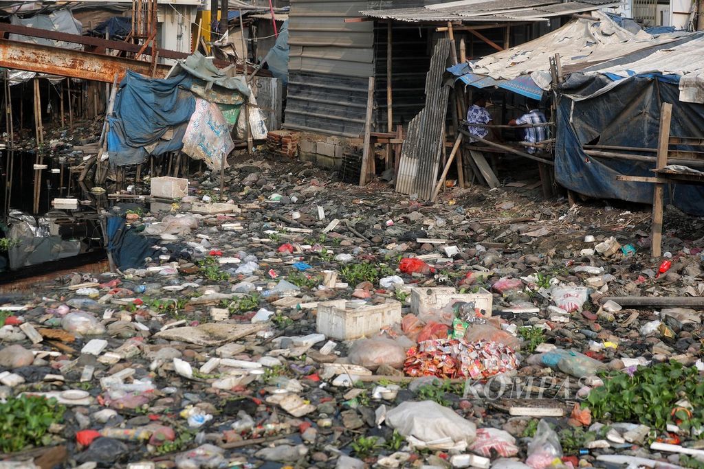 Warga berbincang di atas balai-balai yang berada di tepi Kali Dadap, Kosambi, Tangerang, Banten, yang permukaannya dipenuhi sampah, Minggu (23/5/2021). Sampah itu kebanyakan berupa kantong plastik dan <i>styrofoam</i> yang sulit membusuk. 