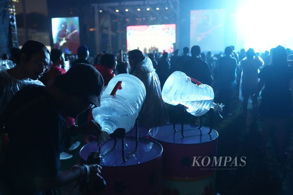 Penonton mengisi ulang air minum dari galon dalam gelaran festival musik Joyland 2023 di Lapangan Baseball, Kompleks Gelora Bung Karno, Senayan, Jakarta, Jumat (24/11/2023).  