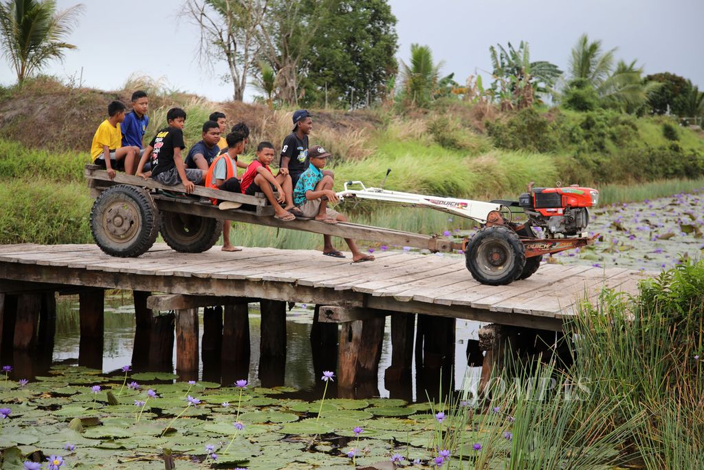 Anak-anak berkeliling areal persawahan menggunakan traktor yang digunakan untuk menarik gerobak yang mereka tumpangi di Kampung Waninggap Kai, Distrik Semangga, Kabupaten Merauke, Papua Selatan, Selasa (23/7/2024). 