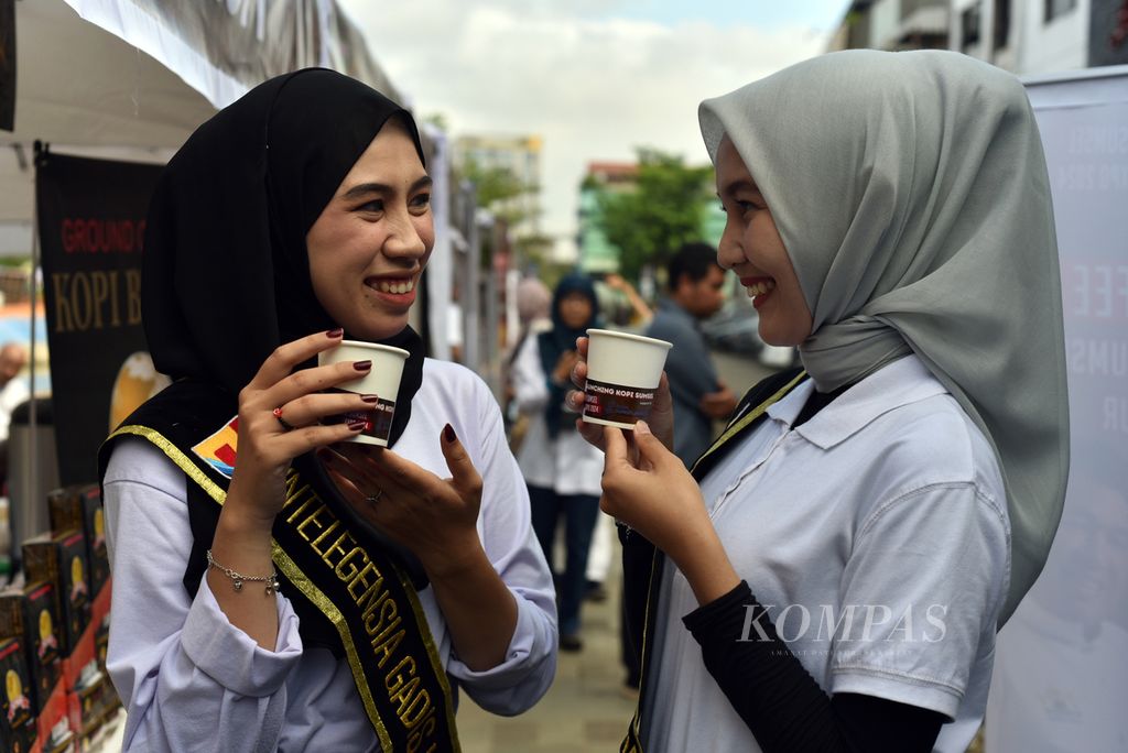 Duta pariwisata dari salah satu universitas swasta di Palembang menikmati kopi di sela acara ”Morning Coffee dan Launching Kopi Sumsel” di Palembang, Sumatera Selatan, Minggu (12/5/2024).