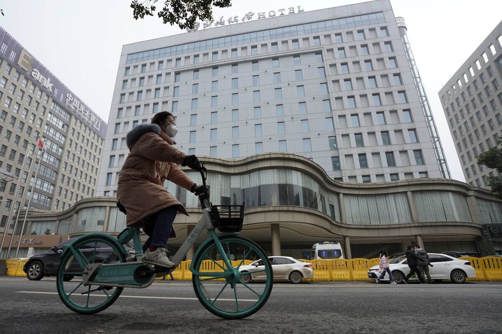 Pesepeda melintas di depan The Jade Boutique Hotel yang digunakan untuk karantina tim ahli WHO selama 14 hari di Wuhan, China, Kamis (28/1/2021).
