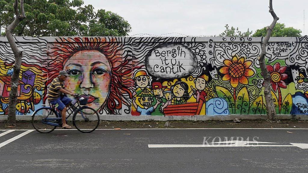 Warga melintasi tembok bermural tema kebersihan di Jalan Pantai Kenjeran, Surabaya, Senin (13/2). Ajakan untuk menjaga kebersihan dilakukan  pemerintah kota salah satunya dengan mural.