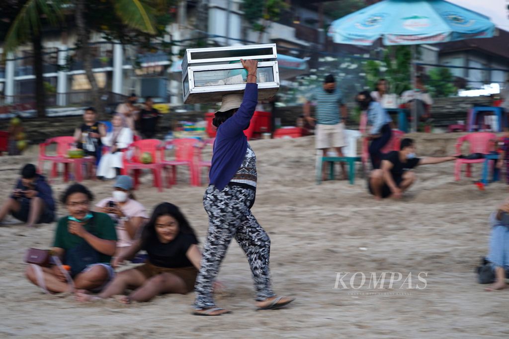 Traders peddle their wares at Kuta Beach, Bali, Monday (11/10/2021).