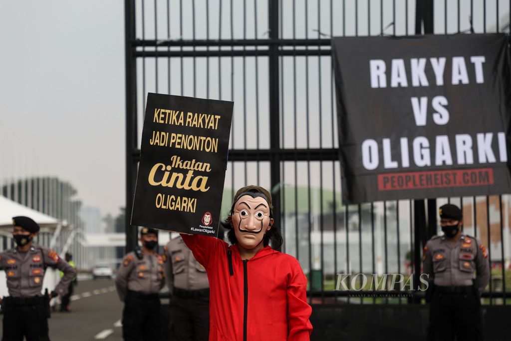 Aktivis yang tergabung dalam People Heist menunjukkan poster yang mereka bawa saat berunjuk rasa di depan Gedung Parlemen, Senayan, Jakarta, Senin (4/10/2021). Mereka, antara lain, menyuarakan dan memperingatkan tentang bahaya oligarki yang semakin merejalela, khususnya pascapengesahan UU Cipta Kerja. 