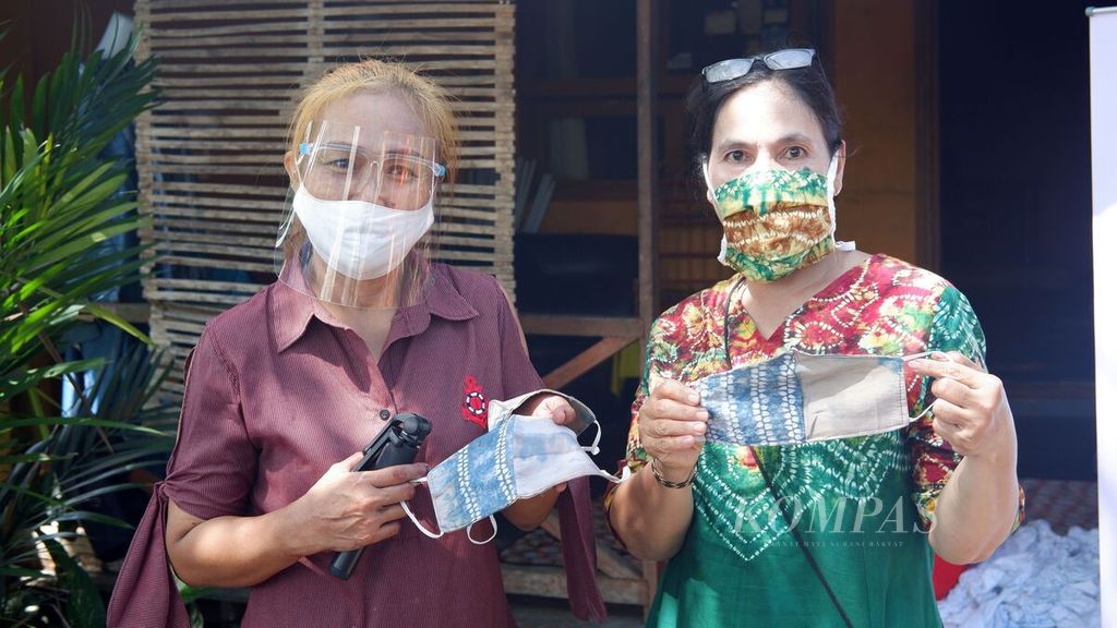 Dua pengrajin kain sasirangan menunjukkan masker yang terbuat dari kain sasirangan berpewarna alami di Kota Banjarmasin, Kalimantan Selatan, Kamis (16/7/2020). Masker kain tersebut dijual seharga Rp 15.000 per lembar.