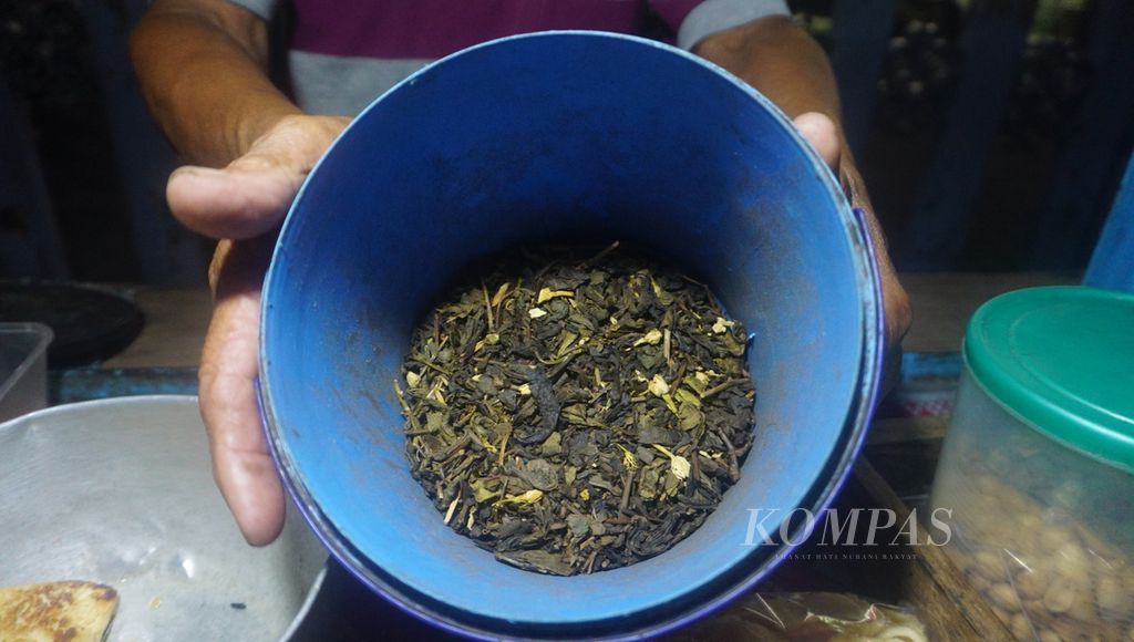 Penjaja <i>wedangan</i> menunjukkan racikan teh oplosannya di Kota Surakarta, Jawa Tengah, Rabu (17/8/2022) malam. Teh oplosan merupakan campuran racikan teh dari beberapa merek. 