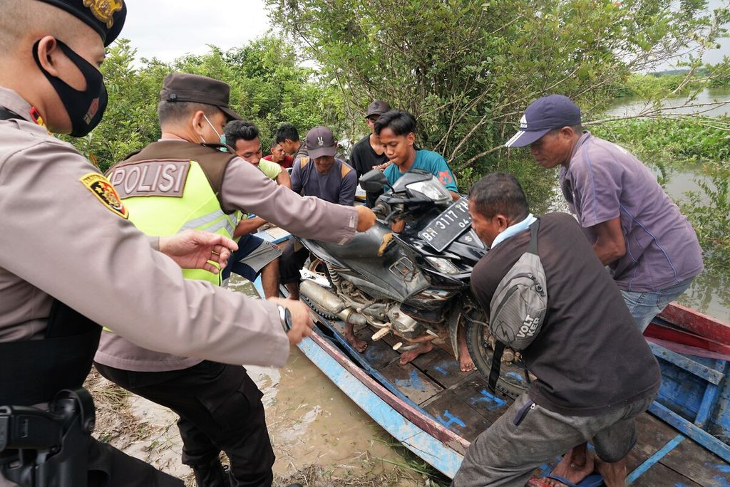Aparat Kepolisian Sektor Mestong membantu warga menurunkan kendaraan yang dievakuasi dari banjir di Desa Nyogan, Mestong, Muaro Jambi, Rabu (9/11/2022). Banjir itu disebabkan meluapnya sejumlah sungai yang ada di sana.