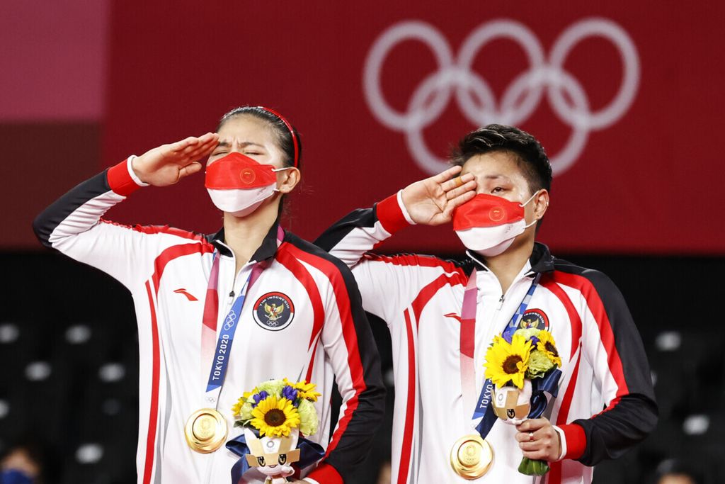 Peraih medali emas ganda putri Olimpiade Tokyo 2020, Greysia Polii (kiri) dan Apriyani Rahayu, memberi hormat kepada bendera Merah Putih saat penyerahan medali di Musashino Forest Sport Plaza, Tokyo, Jepang, 2 Agustus 2021. 