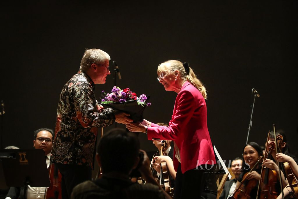Henrik Hochschild (kiri) menerima bunga dari Duta Besar Jerman untuk Indonesia Ina Lepel (kanan) seusai memandu Amadeus Symphony Orchestra dalam konser Bohemian Rhapsody, di Gedung Petra, Jakarta, Rabu (13/9/2023).