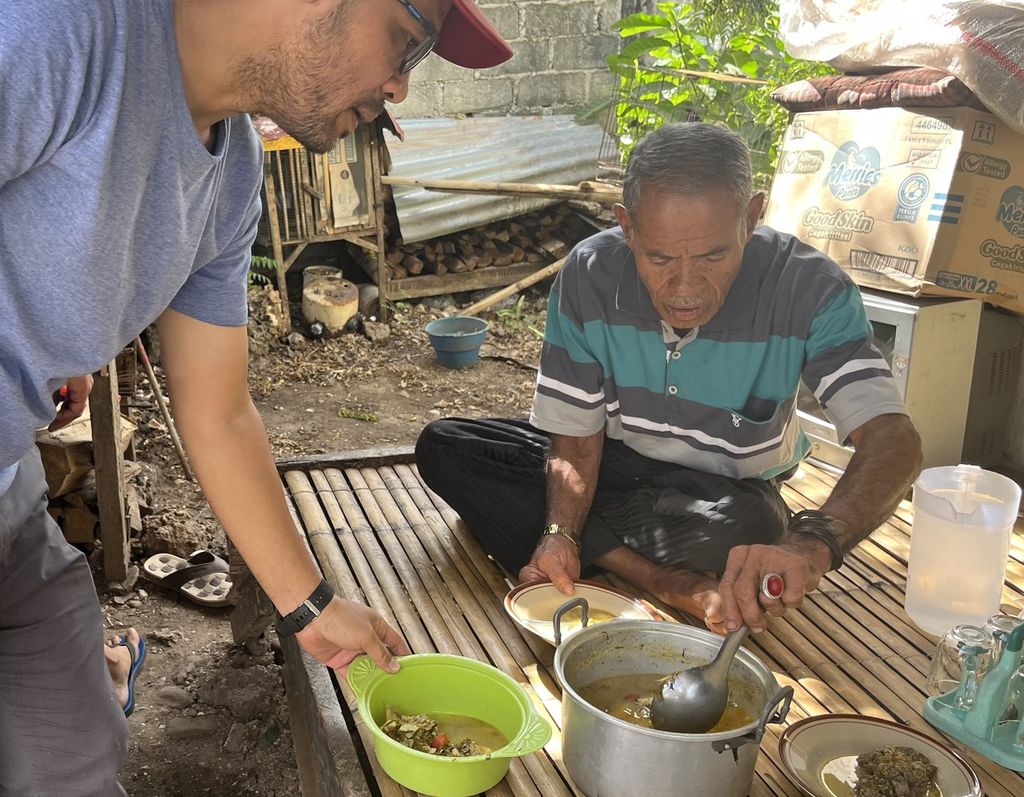 Leno (41), warga Lingkungan Mohuta di Wangi-Wangi Selatan, Pulau Wakatobi, Sulawesi Tenggara mempersilakan La Hambe-hambe (75), sebagai orang yang paling tua untuk mengambil ikan buntal yang telah dimasak, Jumat (1/9/2023), 