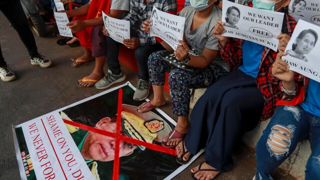 Para pengunjuk rasa membawa foto Aung San Suu Kyi dan menginjak foto pemimpin junta militer Min Aung Hlaing saat berunjuk rasa di Yangon, Myanmar, 11 Februari 2021. 