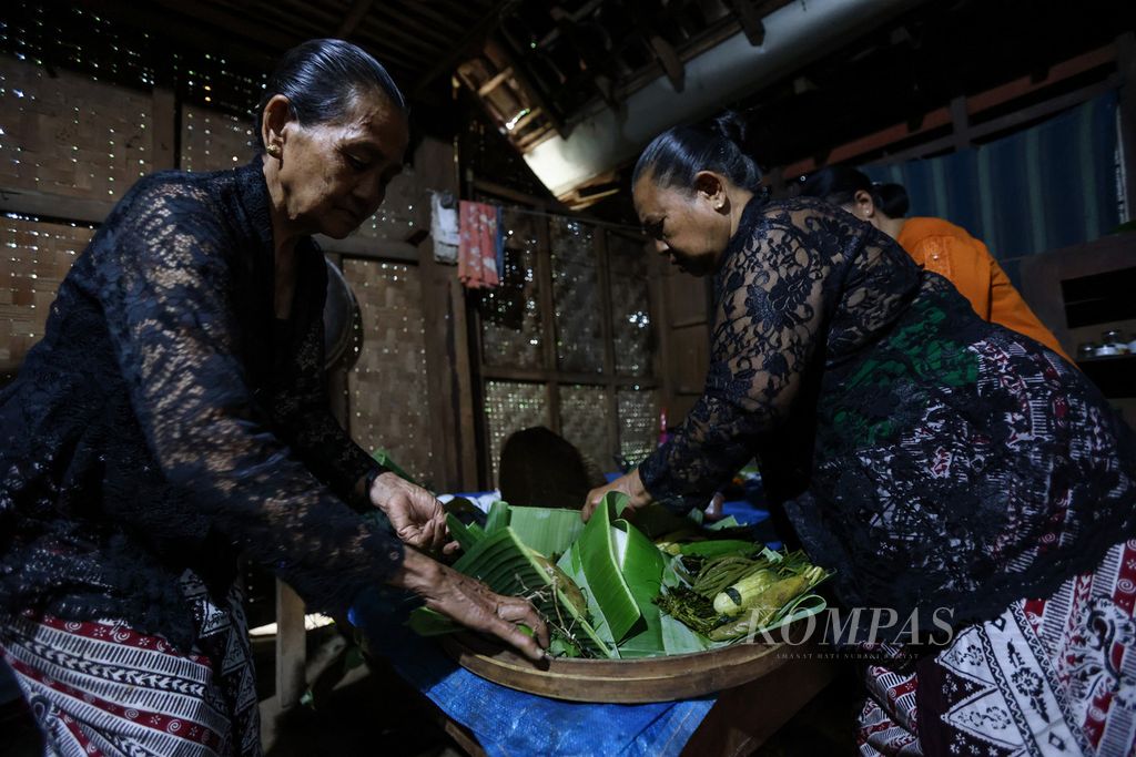 Dua perempuan menyiapkan tumpeng serakat untuk disajikan pada acara selamatan di Desa Kemiren, Kabupaten Banyuwangi, Jawa Timur, Jumat (17/11/2023). Tumpeng serakat adalah menu ritual yang menyimbolkan pengharapan agar warga selamat dan dihindari dari segala halangan serta marabahaya dalam mengarungi hidup. 