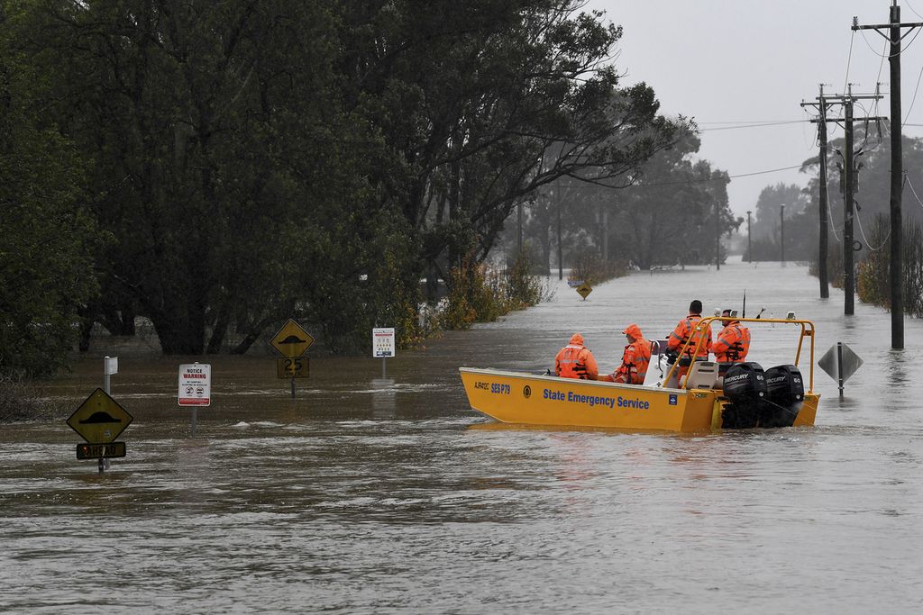 Petugas Layanan Darurat Negara Bagian New South Wales (SES)  melakukan patroli menggunakan perahu evakuasi di sebuah jalan yang terendam banjir akibat luapan Sungai Hawkesbury di Windsor, Sydney, Australia, Senin (4/7/2022). Hujan deras yang melanda Sydney tersebut merupakan salah satu dampak dari perubahan iklim yang kini melanda dunia, termasuk Australia. 
