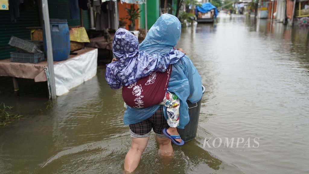 Seorang perempuan menggendong anak sembari membawa ember menembus air bah yang merendam Vila Kencana Cikarang di Desa Karangsentosa, Kecamatan Karangbahagia, Kabupaten Bekasi, Jawa Barat, Kamis (2/3/2023). 