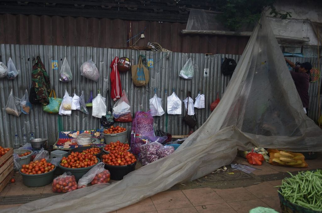Pedagang sayur menyiapkan atap plastik untuk menghindari hujan di Pasar Keputran Utara, Surabaya, Jawa Timur, Senin (13/2/2023). Pasar Keputran Utara menjadi tempat petani sayuran di sekitar Surabaya memasarkan produknya. Sejak pukul 15.00 setiap hari, mobil-mobil pengangkut sayur dari luar kota Surabaya tiba di pasar tersebut. Aktivitas pasar berlangsung hingga dini hari.