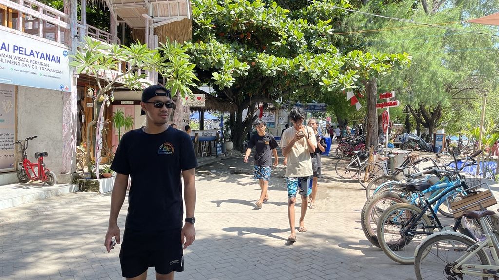 Selain menggunakan sepeda atau cidomo, wisatawan menikmati kawasan Gili Trawangan, Lombok Utara, Nusa Tenggara Barat, dengan berjalan kaki seperti terlihat Minggu (23/1/2022). Hingga saat ini, pariwisata kawasan Gili belum menggeliat akibat dampak dari merebaknya pandemi Covid-19.