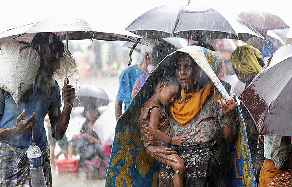 Pengungsi Rohingya  berdiri di ruang terbuka saat hujan deras karena tidak diperbolehkan melintas masuk Banglades oleh  Penjaga Perbatasan Banglades (BGB) dalam upaya melarikan diri dari kerusuhan di Myanmar di pos perbatasan Teknaf, Banglades, Kamis (31/8). 