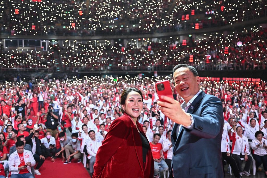 Kandidat perdana menteri dari Partai Pheu Thai, Paetongtarn Shinawatra (kiri) dan Srettha Thavisin (kanan), mengambil swafoto di atas panggung saat kampanye hari terakhir di Bangkok, Thailand, 12 Mei 2023, menjelang pemilu. 