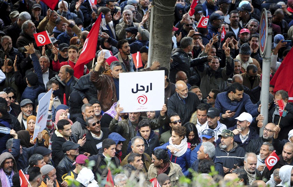 Warga Tunisia berkumpul dalam unjuk rasa menentang Presiden Tunisia Kais Saied di pusat kota Tunis, Tunisia, 14 Januari 2023. Tunisia memperingati 12 tahun Musim Semi Arab. Tulisan pada kertas yang diangkat seorang pengunjuk rasa itu berarti Turunlah. 