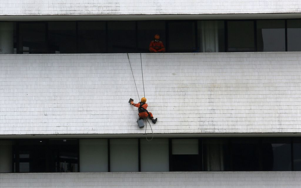 Pekerja pemeliharaan di ketinggian membersihkan dinding sebuah gedung bertingkat, Jumat (1/10/2021). Jumlah masyarakat yang bekerja di sektor informal meningkat selama pandemi Covid-19. 