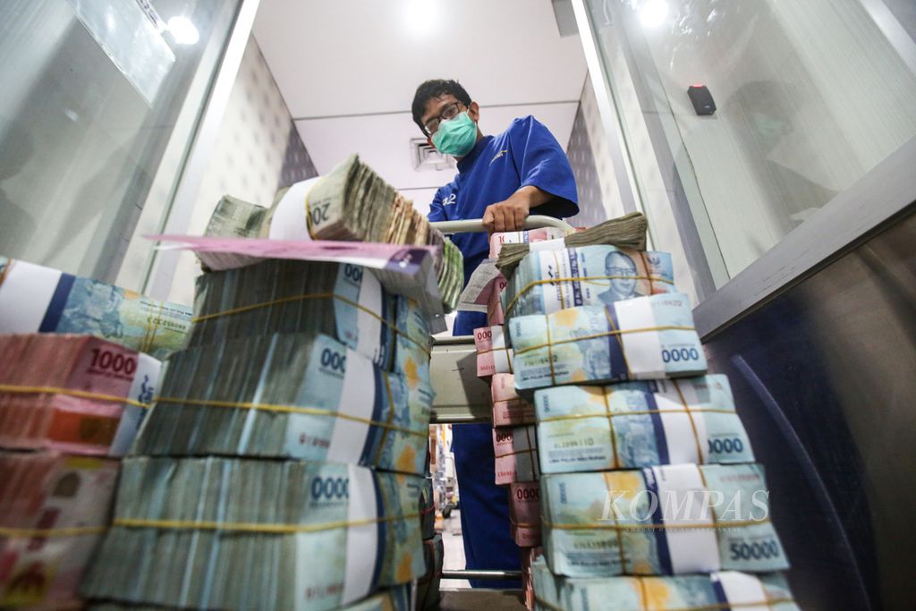 Petugas menarik troli berisi uang rupiah di Cash Pooling Bank Mandiri di Jakarta, Senin (11/12/2023). 