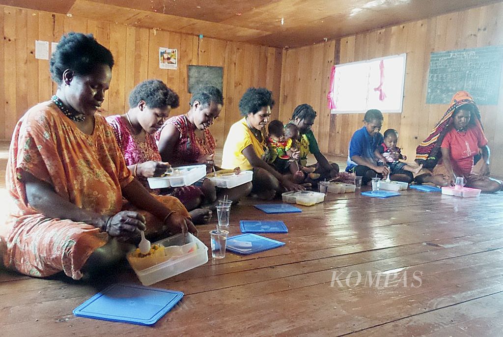 Para ibu menikmati makanan yang dibagikan secara gratis oleh bidan di Posyandu Muara, Kota Karubaga, Kabupaten Tolikara, Papua, pada 27 Juli 2015 lalu. Kegiatan ini merupakan salah satu tahapan dalam Program 1.000 Hari Kehidupan yang terlaksana di Karubaga sejak tahun lalu. Kegiatan ini berhasil menurunkan angka kematian bayi hingga 0 persen. 