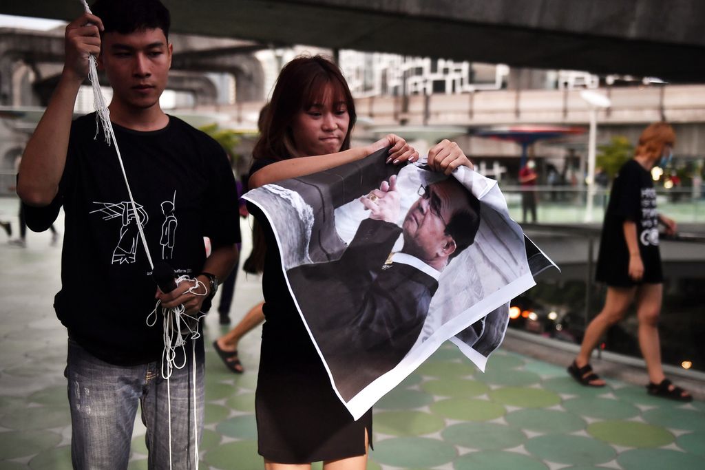 Seorang pengunjuk rasa merobek gambar Perdana Menteri Thailand Prayut Chan-ocha selama demonstrasi menentang usulan pembelian kapal selam oleh pemerintah yang berpihak kepada militer, di Bangkok, Senin (31/8/2020). 