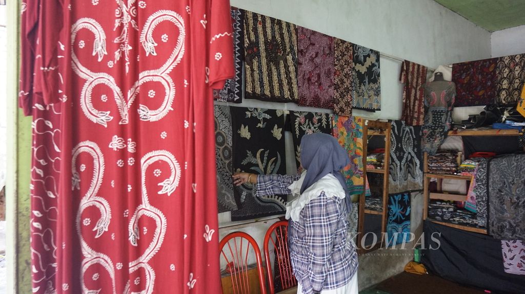 Konsumen batik yang mengaku datang dari Yogyakarta sedang memilih batik tulis warna alam di rumah produksi Mahkota, Bangkalan, Pulau Madura, Jawa Timur, Sabtu (23/7/2022). 