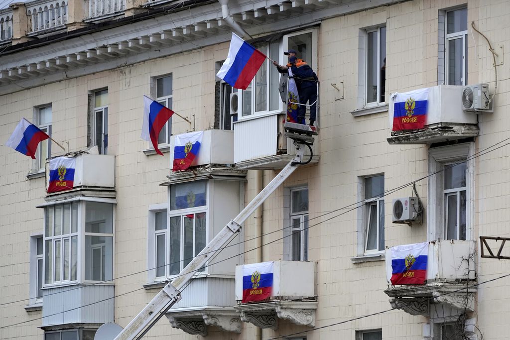 Salah satu kompleks apartemen di Luhanks dipasangi bendera Rusia pada Selasa (27/9/2022). Rusia menggelar pemungutan suara di Donetsk, Luhansk, Zaporizhia, dan Kherson pada 23-27 September 2022. Para pemilih diminta menyetujui atau menolak penggabungan empat wilayah itu dengan Rusia.