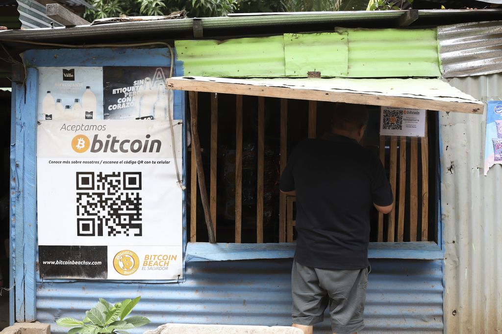 Seorang pekerja di Hope House, sebuah organisasi yang mensponsori penggunaan mata uang kripto, dmelakukan pembelian di sebuah toko kecil yang menerima Bitcoin di Tamanique, El Salvador, Rabu (9/6/2021). (AP Photo/Salvador Melendez)