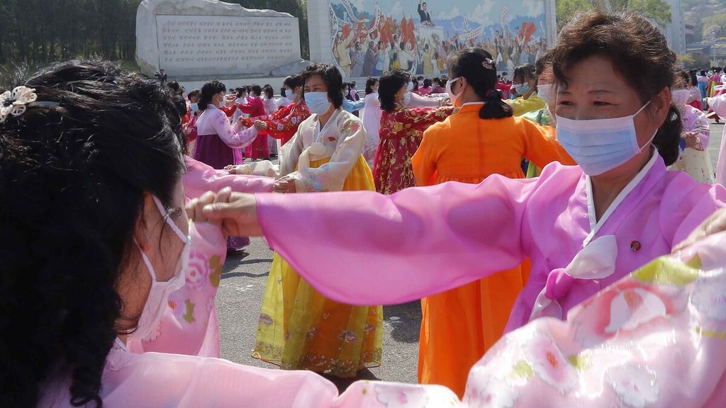 Warga menari dengan memakai pakaian tradisional masyarakat Korea, Hanbok, dan memakai masker meskipun Pemerintah Korea Utara hingga kini masih melaporkan nol kasus virus korona sejak Covid-19 diumumkan sebagai pandemi oleh WHO pada Maret 2020.