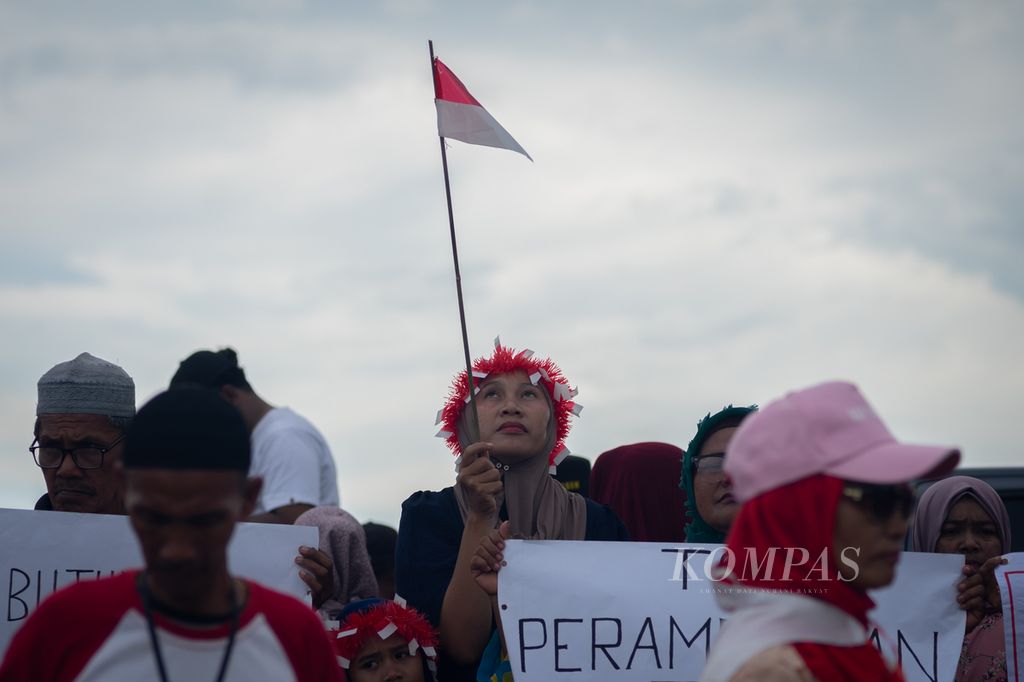 Seorang perempuan menatap bendera merah putih saat pawai Kemerdekaan RI di Pulau Rempang, Batam, Kepulauan Riau, Minggu (18/8/2024).