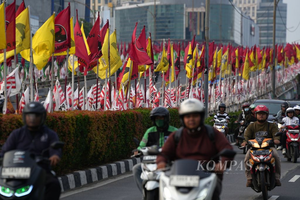 Warga melintasi bendera partai politik di Jalan Pasar Senen, Jakarta Pusat, Senin (1/1/2024). Masa kampanye digunakan partai politik untuk memasang alat peraga kampanye.