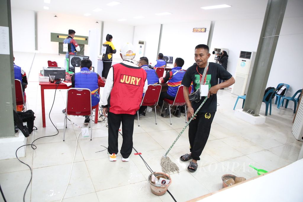 Petugas membersihkan lantai arena perlombaan dari air yang menetes dari plafon saat hujan deras dan angin kencang di Lapangan Tembak Rindam IM Mata Ie, Aceh Besar, Aceh, Rabu (18/9/2024).