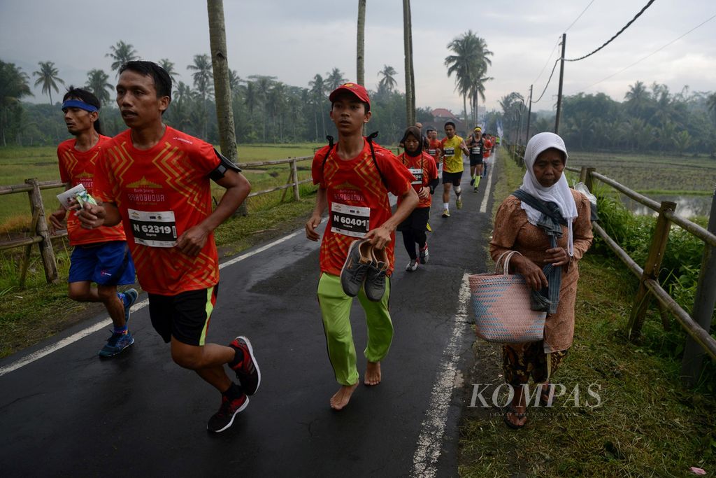 Peserta lomba lari Bank Jateng Borobudur Marathon 2017 melintasi areal persawahan Dusun Ngaran II, Desa Borobudur, Kecamatan Borobudur, Kabupaten Magelang, Jawa Tengah, Minggu (19/11/2017). 