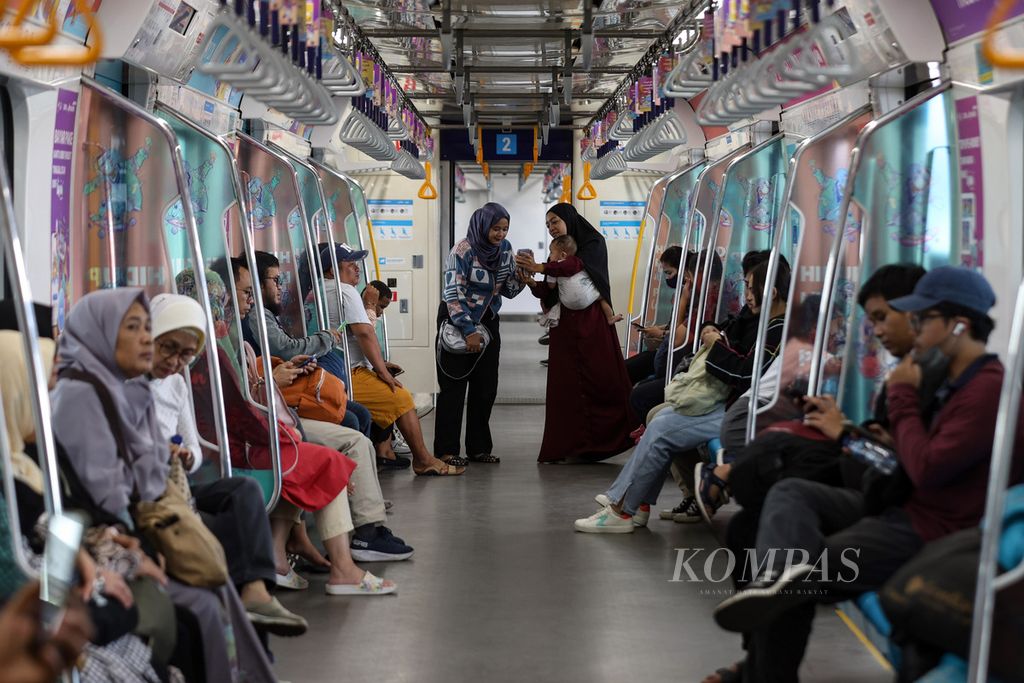 Penumpang berbincang di dalam kereta MRT di Stasiun MRT Lebak Bulus, Jakarta Selatan, Jumat (19/4/2024).