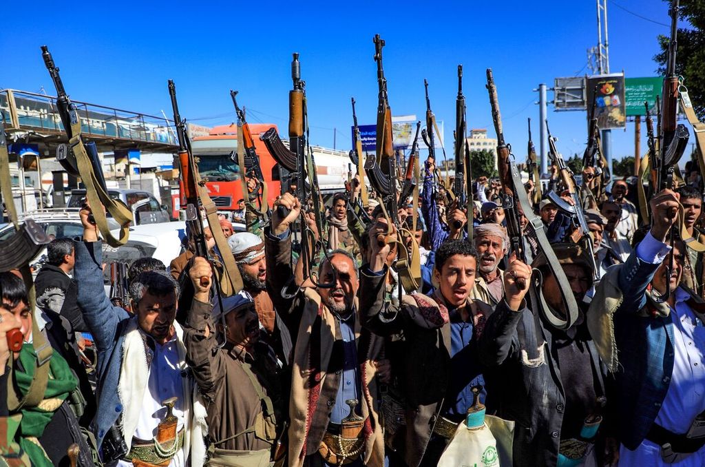Milisi Houthi mengacungkan senjata mereka dalam sebuah demonstrasi di Ibu kota Yaman, Sanaa, memprotes intervensi koalisi Arab yang dipimpin Arab Saudi. Unjuk rasa digelar pada Kamis (27/1/2022).