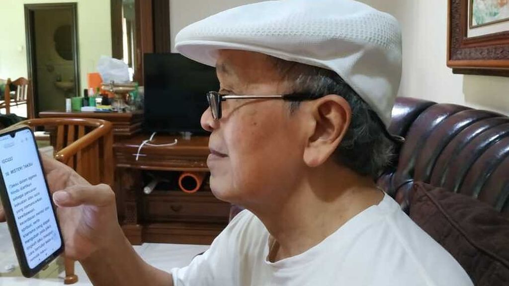 Sastrawan Putu Wijaya (78) sedang menulis di telepon seluler dengan hanya menggunakan jempol tangan kanan, Rabu (2/3/2022).