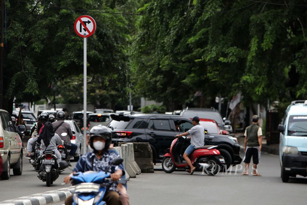 Pengatur lalu lintas atau biasa disebut Pak Ogah membantu kendaraan yang akan putar balik di Jalan Palmerah Utara, Tanah Abang, Jakarta, Minggu (12/2/2023). 